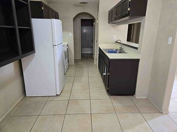 Brownsville house for rent - A kitchen with a white refrigerator and black cabinets.
