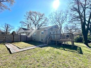 Greenville house for rent - A house with a deck and a fence is surrounded by trees.