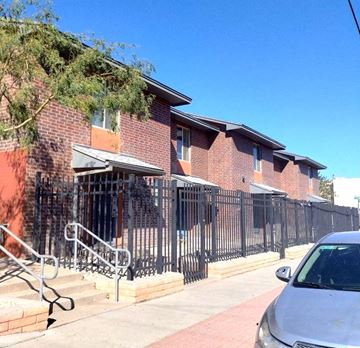 El Paso apartment for rent - A brick building with a black iron fence and a silver car parked in front.