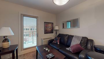 Fort Mcmurray house for rent - A living room with a black couch and a lamp on a table.
