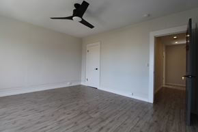 Berkeley apartment for rent - A room with a ceiling fan and light fixture, a door, and a wooden floor.