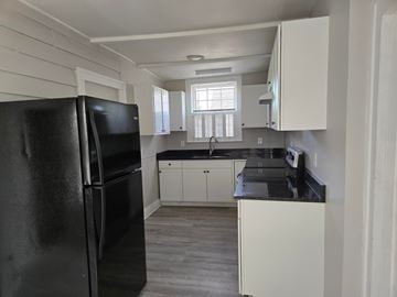 Warrenton apartment for rent - A black refrigerator is in a kitchen with white cabinets.