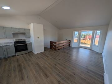 Woodland Park apartment for rent - A spacious room with wooden flooring and a kitchen area with a stove and oven.