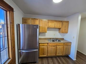 Woodland Park apartment for rent - A kitchen with a stainless steel refrigerator and wooden cabinets.