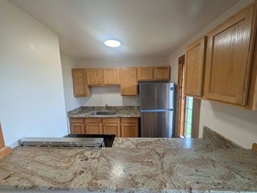 Woodland Park apartment for rent - A kitchen with wooden cabinets and a granite countertop.