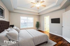 Clarksville house for rent - A bedroom with a bed, a ceiling fan, and a television.