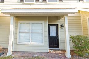 Freeport house for rent - A house with a black door and window is numbered 56.