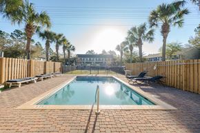 Freeport house for rent - A pool surrounded by palm trees and wooden fences.