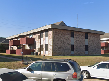 Deridder apartment for rent - A silver car is parked in front of a building with a red and white striped wall.