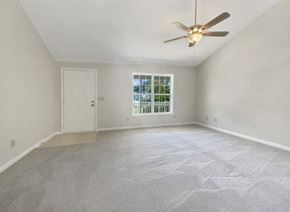 Winston-Salem house for rent - A room with a ceiling fan and a window with a view of trees.