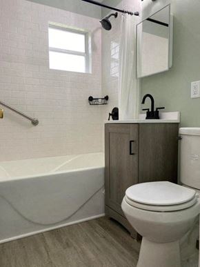 Gary house for rent - A white toilet sits next to a white bathtub in a bathroom.