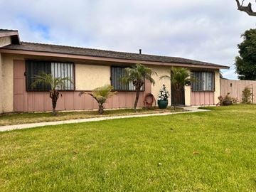 Oxnard house for rent - A house with a green lawn and a tree in front.