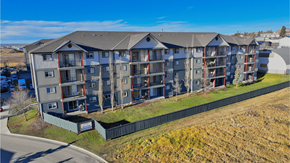 Dawson Creek apartment for rent - A large apartment complex with multiple balconies and a green fence in front.