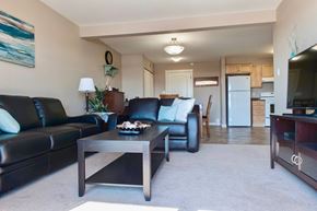 Dawson Creek apartment for rent - A living room with a black leather couch, a wooden coffee table, and a television.