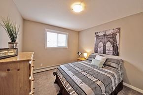 Dawson Creek apartment for rent - A bedroom with a bed, nightstand, and a plant.