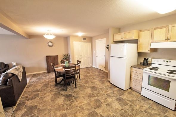 Dawson Creek apartment for rent - A kitchen with white appliances and a brown tiled floor.