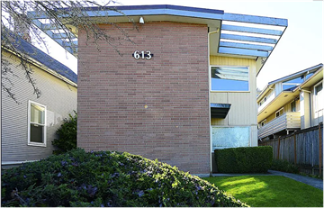 Seattle apartment for rent - A house numbered 613 with a green bush in front.