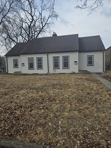 St. Louis Park apartment for rent - A small house with a grey roof and white walls is surrounded by a field of dry leaves.