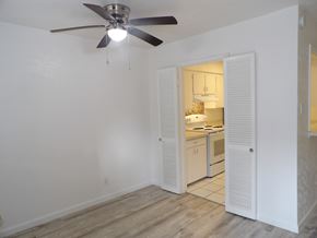 Dallas apartment for rent - A room with a ceiling fan and a kitchen area in the background.