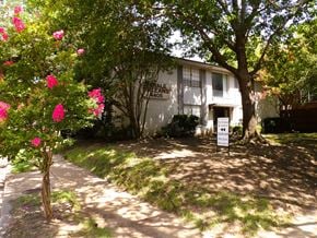 Dallas apartment for rent - A white sign with black text is in front of a house.