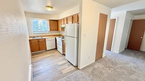 Wheat Ridge apartment for rent - A long building with a green roof and a parking lot in front.