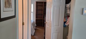 Sarasota house for rent - A hallway with a white door and a bedroom with a bed and a bookshelf.