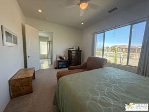 Rancho Mirage house for rent - A bedroom with a large bed and a view of the backyard through the window.