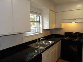 Dallas apartment for rent - A kitchen with black countertops and white cabinets.