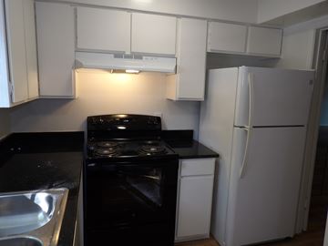 Dallas apartment for rent - A black stove top oven sits next to a white refrigerator in a kitchen.