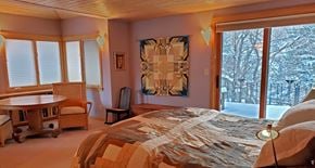 Boulder house for rent - A bedroom with a bed, chair, and window.
