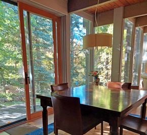 Boulder house for rent - A dining room with a table and chairs and a view of trees outside.