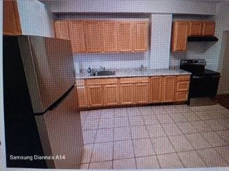 Baltimore house for rent - A kitchen with wooden cabinets and a black stove.