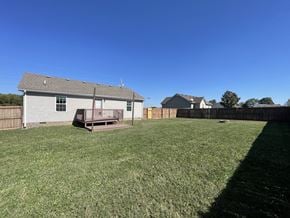 Portland house for rent - A house with a grey roof and a wooden deck is surrounded by a grassy field.