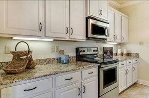 Lafayette house for rent - A kitchen with white cabinets and a granite countertop.