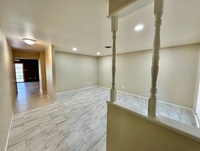 Bay City house for rent - A spacious room with a wooden floor and a staircase with a white railing.