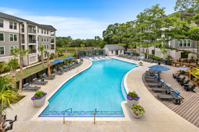 Charleston apartment for rent - A large swimming pool surrounded by lounge chairs and umbrellas.