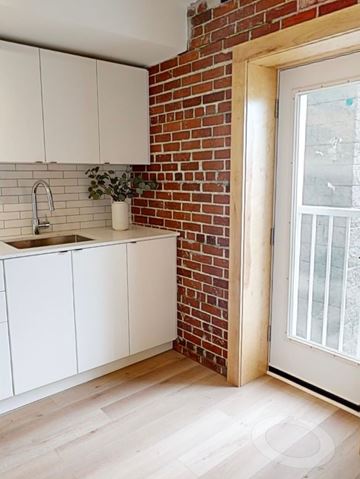 Halifax apartment for rent - A kitchen with white cabinets and a brick wall.