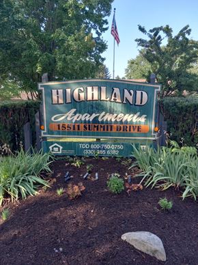 East Liverpool apartment for rent - A sign for Highland Apartments is displayed in front of a hedge.