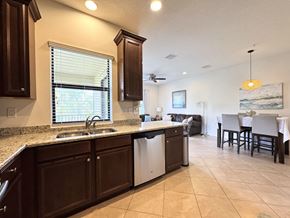 Bradenton house for rent - A kitchen with brown cabinets and a white dishwasher.