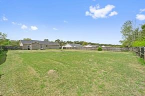 Richlands house for rent - A large grassy field with a house and fence in the background.
