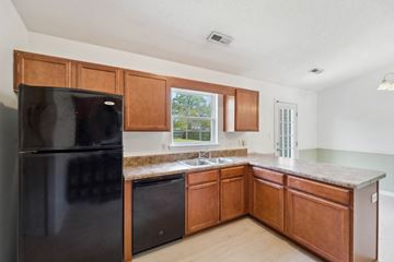 Richlands house for rent - A black refrigerator is in a kitchen with wooden cabinets.