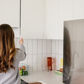 Victoria apartment for rent - A woman is opening a white cabinet in a kitchen.