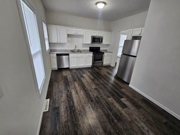 Lima house for rent - A kitchen with white cabinets and a wooden floor.