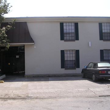 New Orleans apartment for rent - A black car is parked in front of a white building with black shutters.
