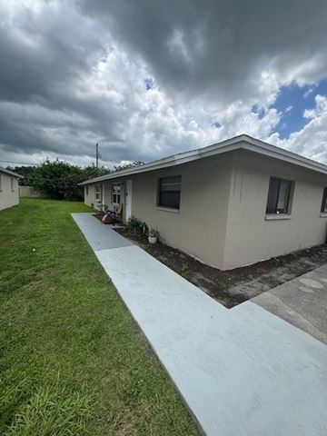 Fort Myers apartment for rent - A house with a concrete walkway leading to the front door.