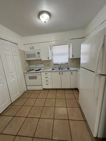 Fort Myers apartment for rent - A kitchen with white appliances and brown tiles.