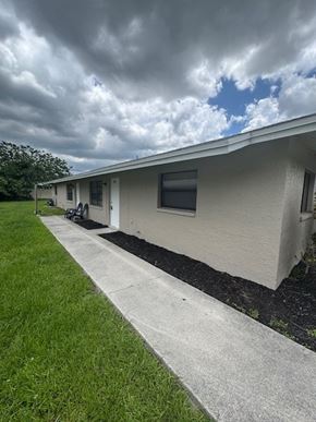 Fort Myers apartment for rent - A house with a grey roof and a white wall with a black window.