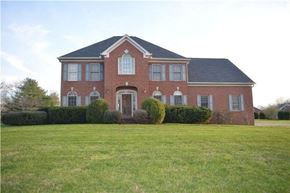 Brentwood house for rent - A red brick house with a black roof and a green lawn in front.