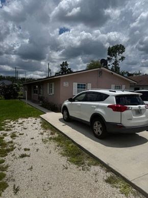 Fort Myers apartment for rent - A white car is parked in front of a pink house.