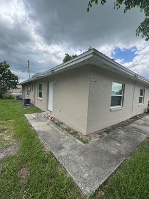 Fort Myers apartment for rent - A house with a grey roof and a white door is surrounded by grass.